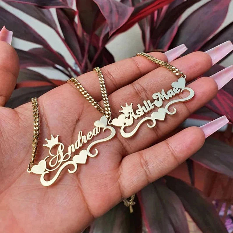 Gold name necklaces on a hand with a plant in the background