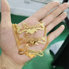 Gold necklaces with engraved names held in a hand against a blurred background