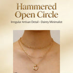 A gold-toned layered necklace with an open hammered circle pendant, shown worn on a model's neck against a soft beige background with the text 'Hammered Open Circle' and 'Irregular Artisan Detail • Dainty Minimalist'.