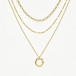 A layered gold necklace set featuring three distinct chain styles and a twisted oval pendant, displayed on a clean white background.