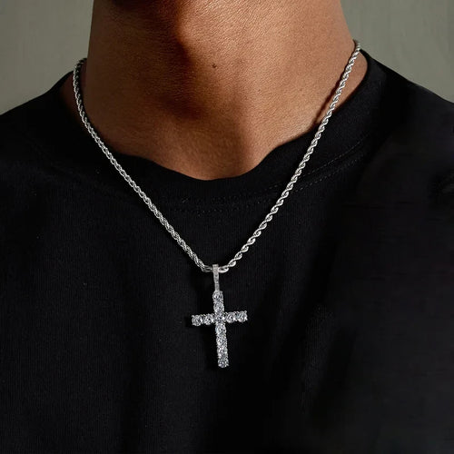 Person wearing a silver cross necklace on a plain background