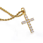 A gold cross pendant necklace paved with clear cubic zirconia stones, shown on a gold rope chain against a white background.