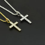 Two cross-shaped pendants on chains against a dark background