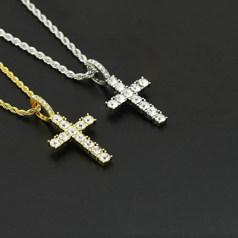 Two cross-shaped pendants on chains against a dark background