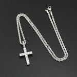 Silver chain necklace with a cross pendant on a dark background