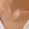 A delicate gold chain necklace with a pendant shaped like two interlocking infinity loops, one of which is set with small clear stones, worn on a model's neck.