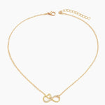 A delicate gold chain necklace featuring an infinity symbol pendant adorned with small clear crystals, displayed on a clean white background.