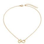 A delicate gold chain necklace featuring a double infinity symbol pendant, one of which is adorned with small clear crystals. The necklace is displayed on a clean white background.