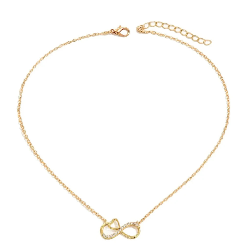 A delicate gold chain necklace featuring a double infinity symbol pendant, one of which is adorned with small clear crystals. The necklace is displayed on a clean white background.