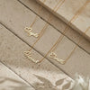 Three gold name necklaces on a stone surface