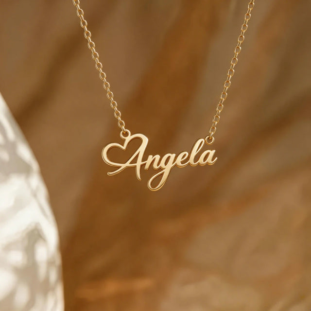 Gold necklace with 'Angela' pendant on a warm brown background