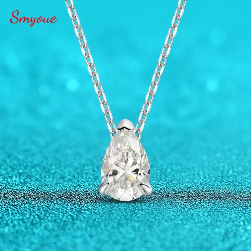 Teardrop-shaped diamond pendant on a chain against a turquoise background