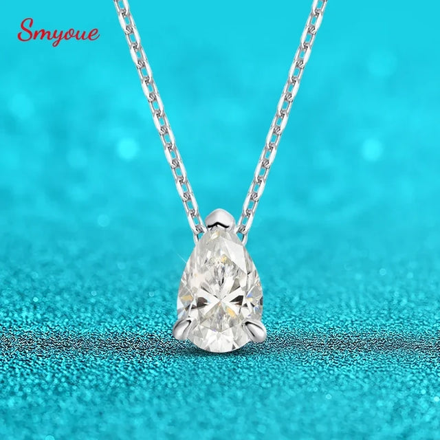 Teardrop-shaped diamond pendant on a chain against a turquoise background