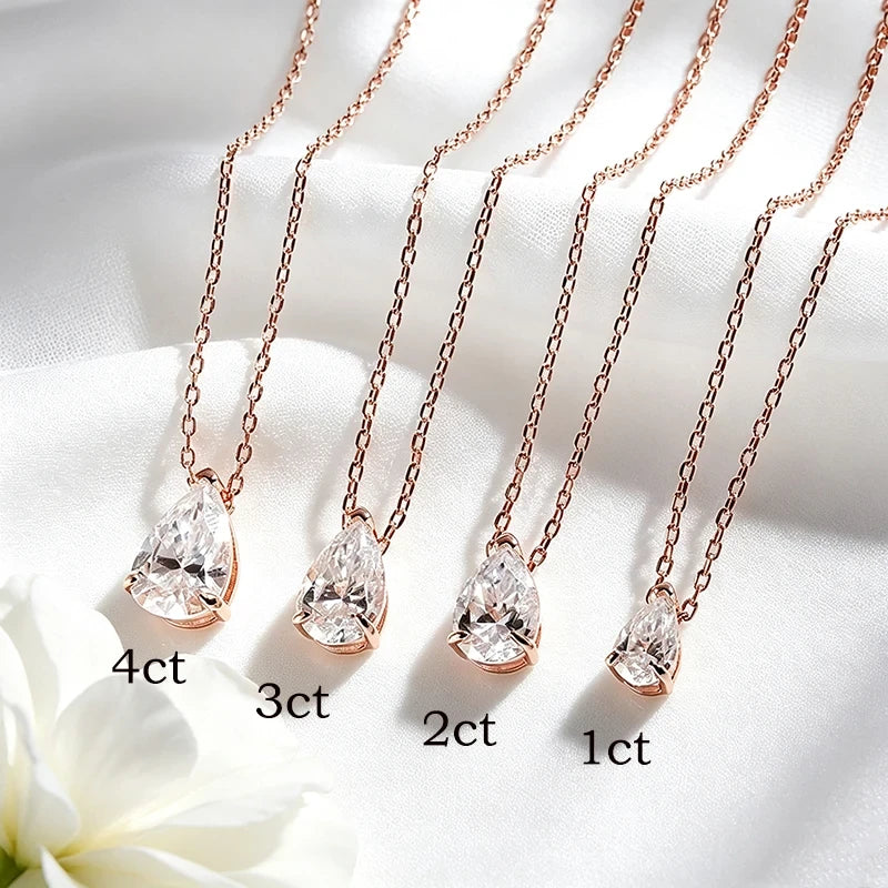 Four rose gold necklaces with pear-cut clear crystals are arranged diagonally on white satin fabric, with text labels indicating 4ct, 3ct, 2ct, and 1ct sizes.