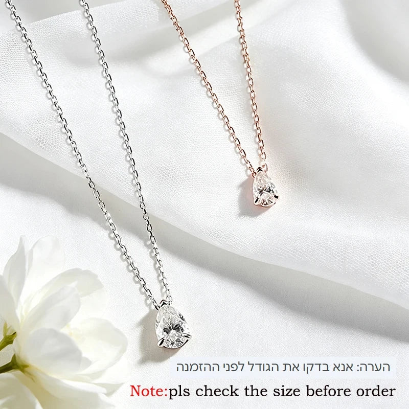 Two heart-shaped crystal pendant necklaces, one silver and one rose gold, displayed on a white fabric background with a white flower in the corner.