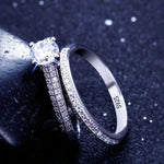 Silver ring with a large central gemstone and smaller stones on a dark background