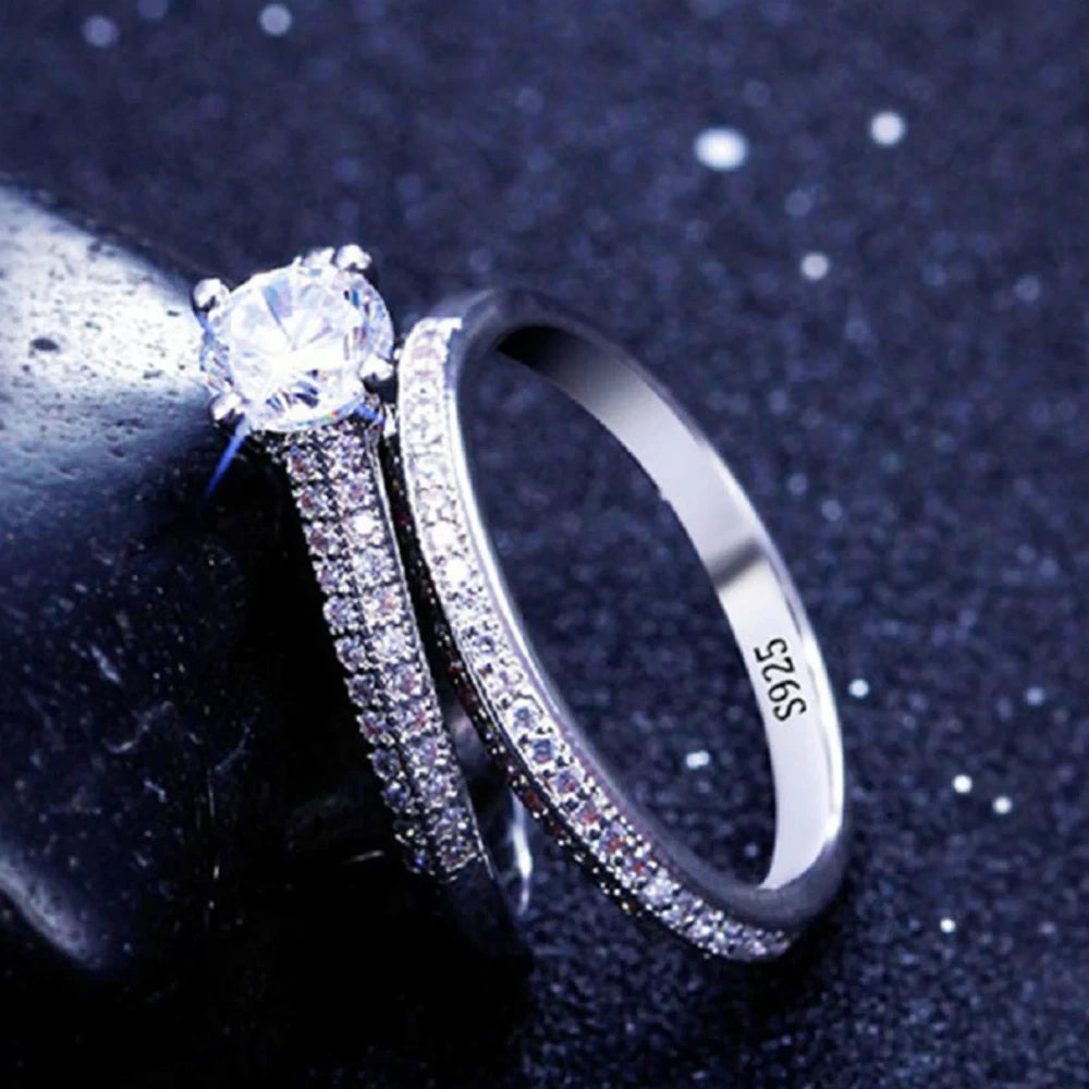 Silver ring with a large central gemstone and smaller stones on a dark background