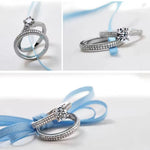 Silver ring with a diamond on a light blue ribbon against a white background